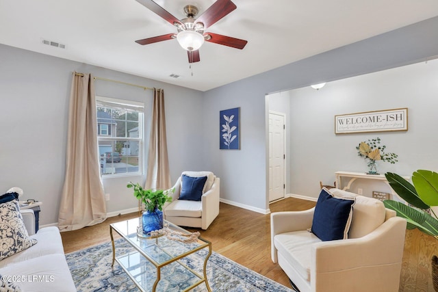 living room with visible vents, baseboards, and wood finished floors