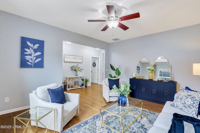 living area with ceiling fan, visible vents, baseboards, and wood finished floors