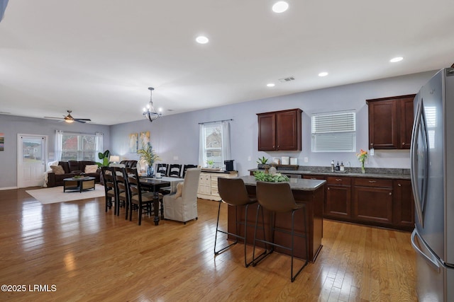 kitchen featuring a breakfast bar, light wood finished floors, recessed lighting, freestanding refrigerator, and a kitchen island