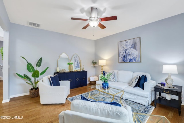 living area with baseboards, visible vents, ceiling fan, and wood finished floors