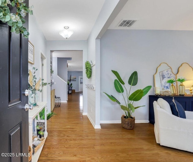 foyer with light wood finished floors, baseboards, and visible vents