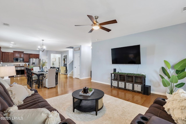 living area with light wood finished floors, visible vents, and baseboards