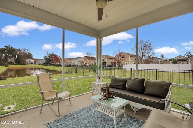 sunroom / solarium with a water view, ceiling fan, and a residential view