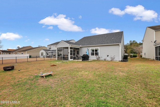 rear view of house featuring a sunroom, fence, and a yard