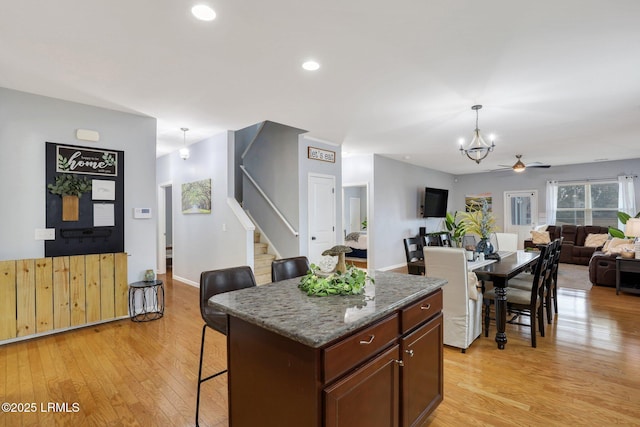 kitchen featuring open floor plan, hanging light fixtures, a center island, light wood finished floors, and a kitchen bar