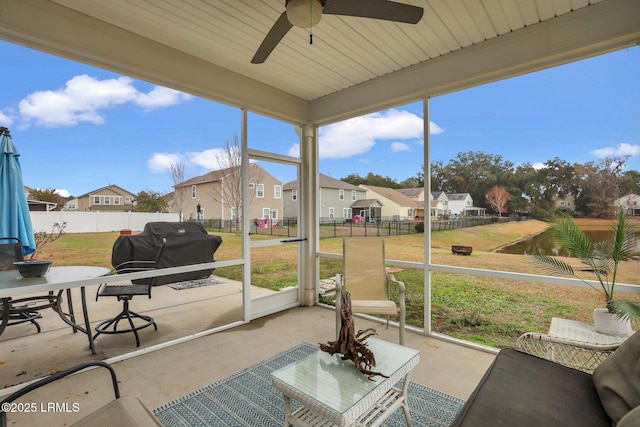 sunroom / solarium with a healthy amount of sunlight, a residential view, and a ceiling fan