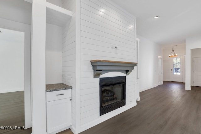 unfurnished living room featuring recessed lighting, a large fireplace, an inviting chandelier, baseboards, and dark wood-style flooring