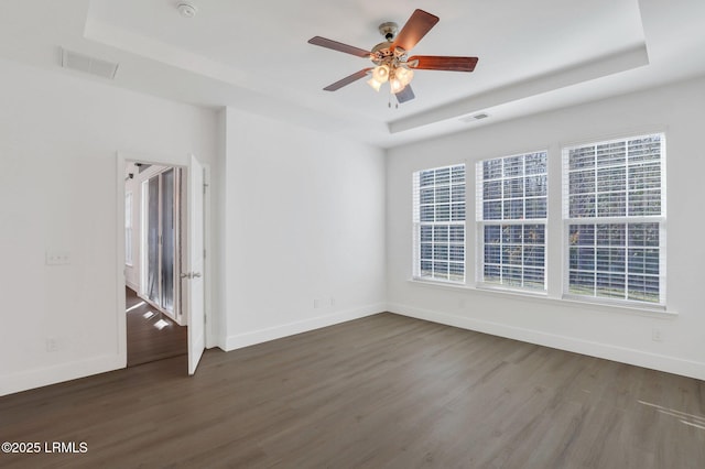 unfurnished room with dark wood finished floors, visible vents, and a raised ceiling