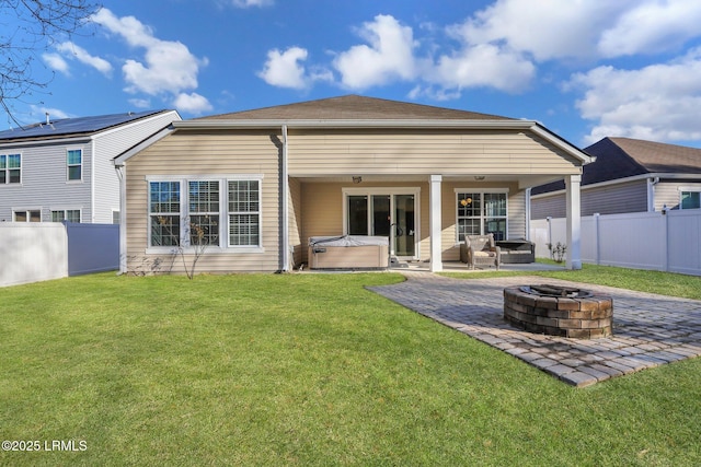 rear view of property with a hot tub, an outdoor fire pit, a lawn, a fenced backyard, and a patio area