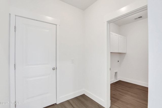 hall with visible vents, baseboards, and dark wood-type flooring