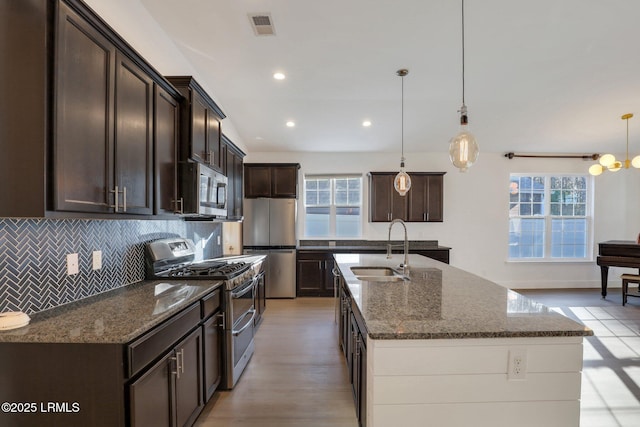 kitchen featuring visible vents, a sink, tasteful backsplash, appliances with stainless steel finishes, and dark brown cabinets