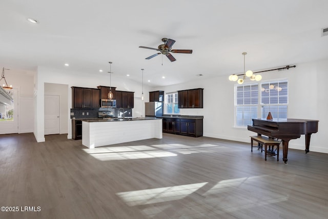 kitchen featuring fridge, wood finished floors, dark brown cabinetry, stainless steel microwave, and backsplash