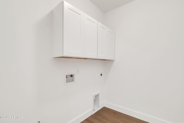 clothes washing area with electric dryer hookup, washer hookup, wood finished floors, cabinet space, and baseboards