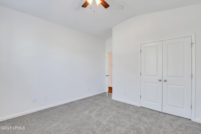 unfurnished bedroom featuring a closet, baseboards, carpet flooring, lofted ceiling, and ceiling fan