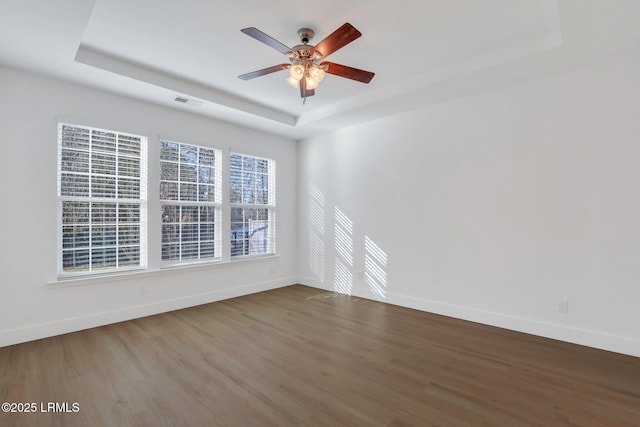 spare room featuring baseboards, a tray ceiling, and wood finished floors