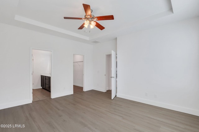 unfurnished room featuring baseboards, a raised ceiling, wood finished floors, and a ceiling fan