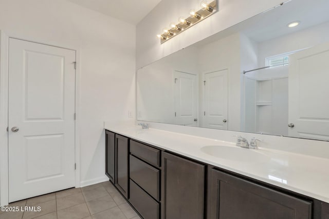 full bath featuring double vanity, tile patterned floors, and a sink