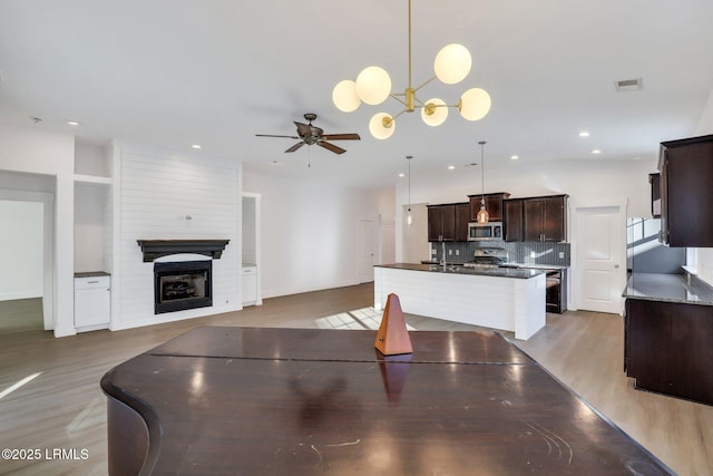 dining area featuring wood finished floors, visible vents, recessed lighting, ceiling fan with notable chandelier, and a large fireplace