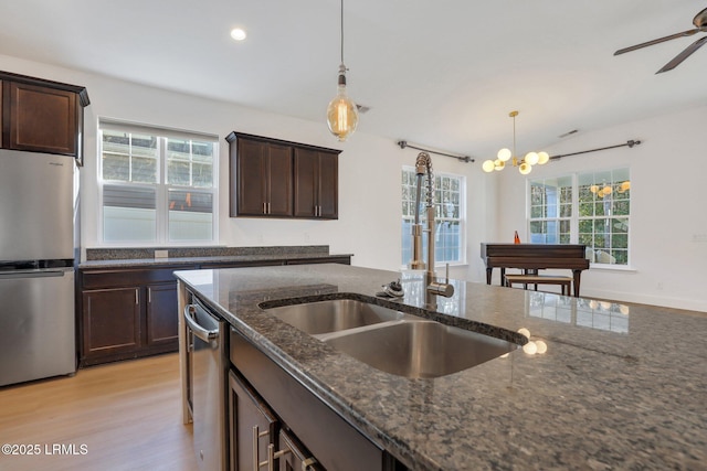 kitchen featuring dark stone countertops, decorative light fixtures, dark brown cabinets, and stainless steel appliances