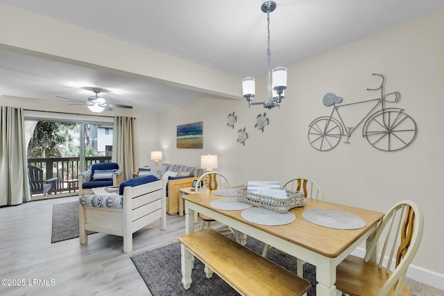 dining room featuring ceiling fan with notable chandelier and light hardwood / wood-style floors