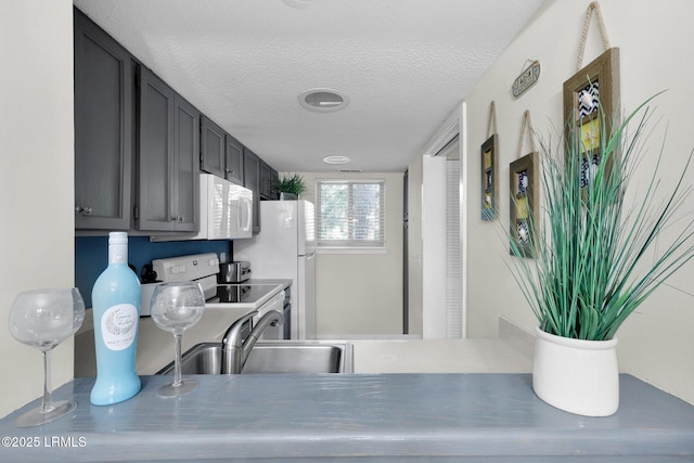 kitchen with sink, white appliances, and a textured ceiling