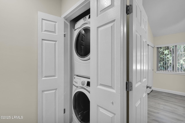 washroom with light wood-type flooring and stacked washer / dryer