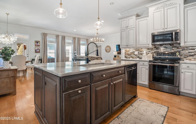 kitchen featuring an inviting chandelier, appliances with stainless steel finishes, sink, and hanging light fixtures