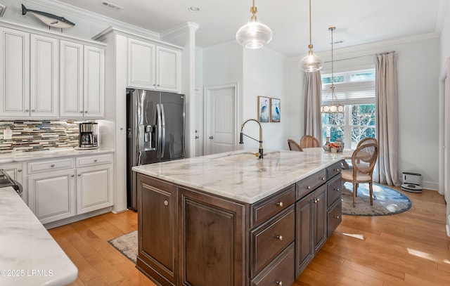 kitchen with sink, decorative light fixtures, white cabinets, and stainless steel refrigerator with ice dispenser