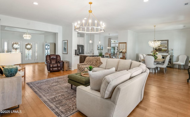 living room featuring ornamental molding, light hardwood / wood-style floors, and a chandelier