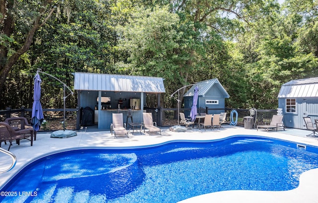 view of pool featuring a bar, an outdoor structure, and a patio area