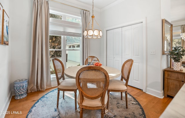 dining space with crown molding and light hardwood / wood-style flooring