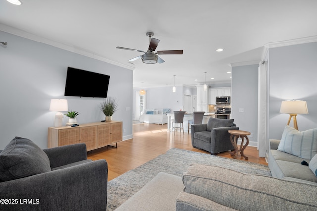 living room with crown molding, ceiling fan, and light hardwood / wood-style floors