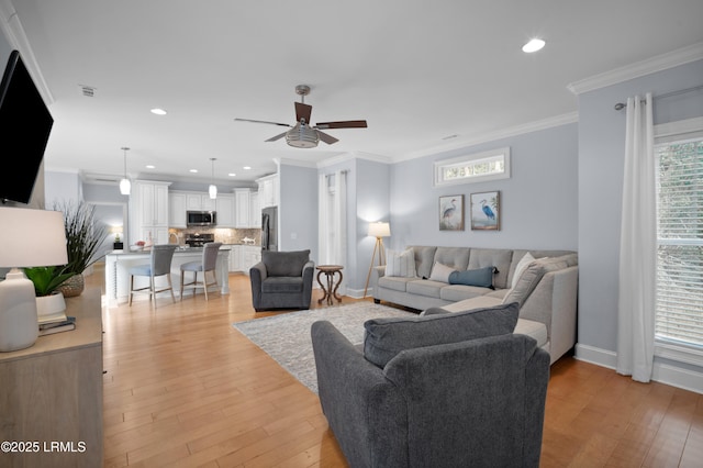 living room featuring ornamental molding, ceiling fan, and light wood-type flooring