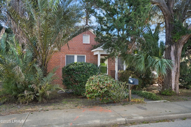 view of property hidden behind natural elements featuring brick siding