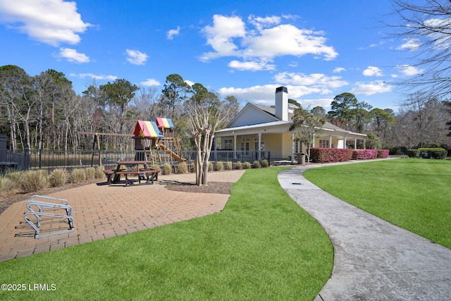 exterior space with a playground, a yard, fence, and a chimney