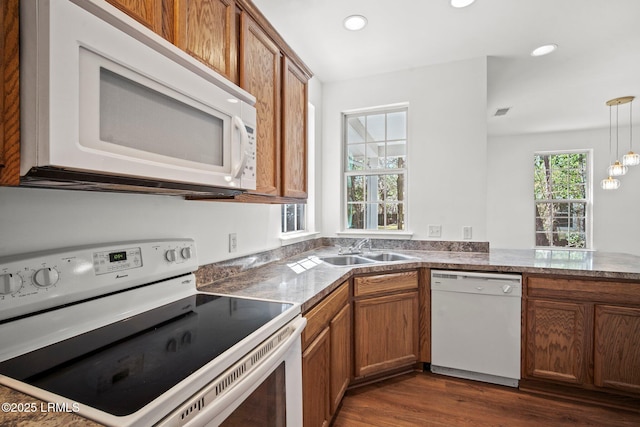 kitchen with a sink, white appliances, brown cabinets, and dark wood-style flooring