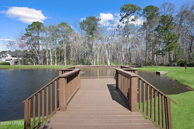 view of dock with a lawn and a water view