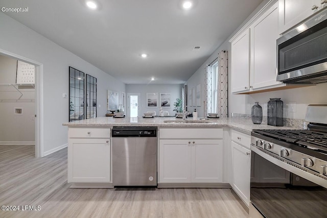 1530 Sanctum St, Ridgeland, SC 29936 - kitchen featuring stainless steel appliances, light wood-style floors, a peninsula, a sink, and white cabinets
