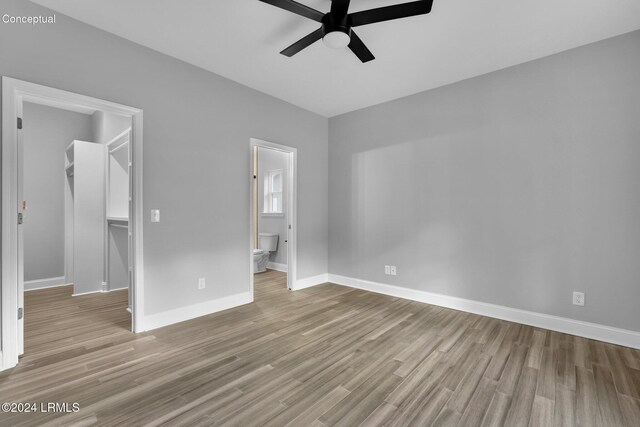 unfurnished bedroom with ceiling fan, ensuite bath, light hardwood / wood-style flooring, and a walk in closet