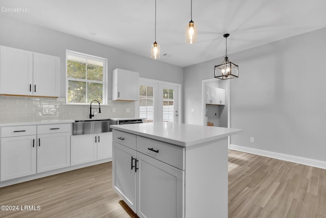 kitchen with sink, a kitchen island, white cabinets, pendant lighting, and backsplash