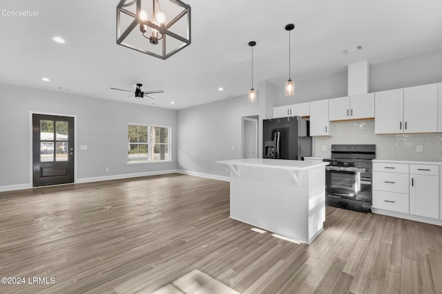 kitchen featuring white cabinetry, tasteful backsplash, a center island, light hardwood / wood-style flooring, and black appliances