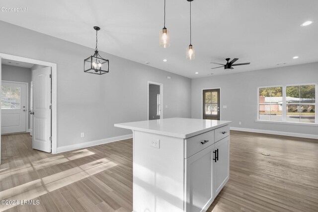 kitchen with white cabinetry, pendant lighting, light wood-type flooring, and a kitchen island