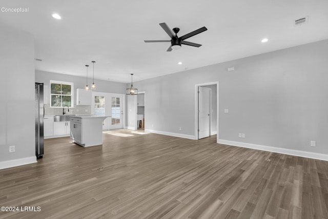 unfurnished living room with hardwood / wood-style flooring, ceiling fan, and sink