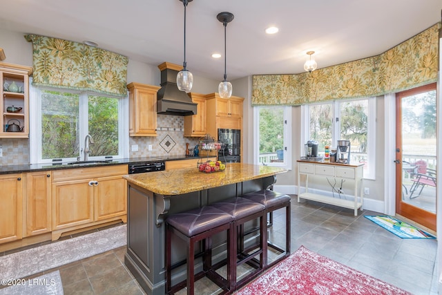 kitchen with premium range hood, a kitchen island, sink, a kitchen breakfast bar, and light stone counters