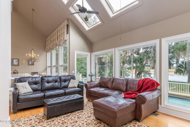 sunroom with ceiling fan with notable chandelier, lofted ceiling with skylight, and a healthy amount of sunlight