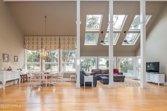 living room with light wood-type flooring, a skylight, plenty of natural light, and a high ceiling