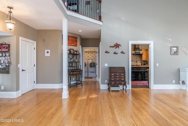 entryway featuring hardwood / wood-style flooring, a towering ceiling, and washer and clothes dryer