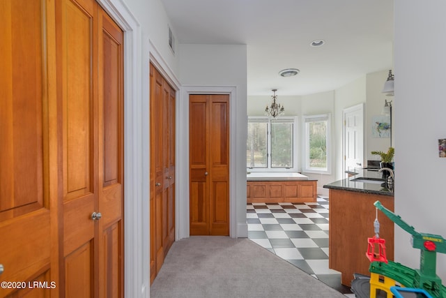 corridor featuring sink and a notable chandelier