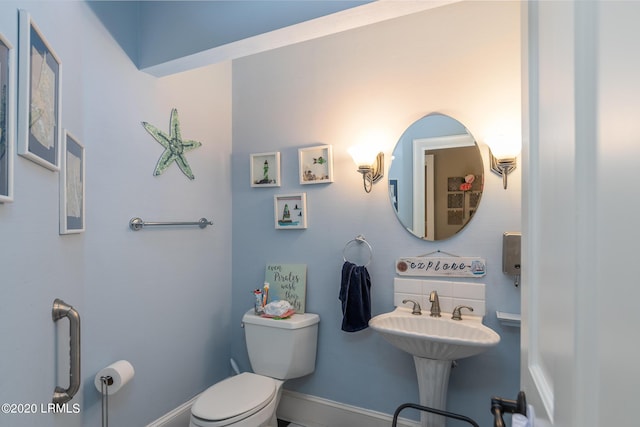 bathroom with toilet, sink, and decorative backsplash