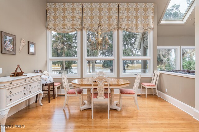 dining space with light hardwood / wood-style flooring and a skylight